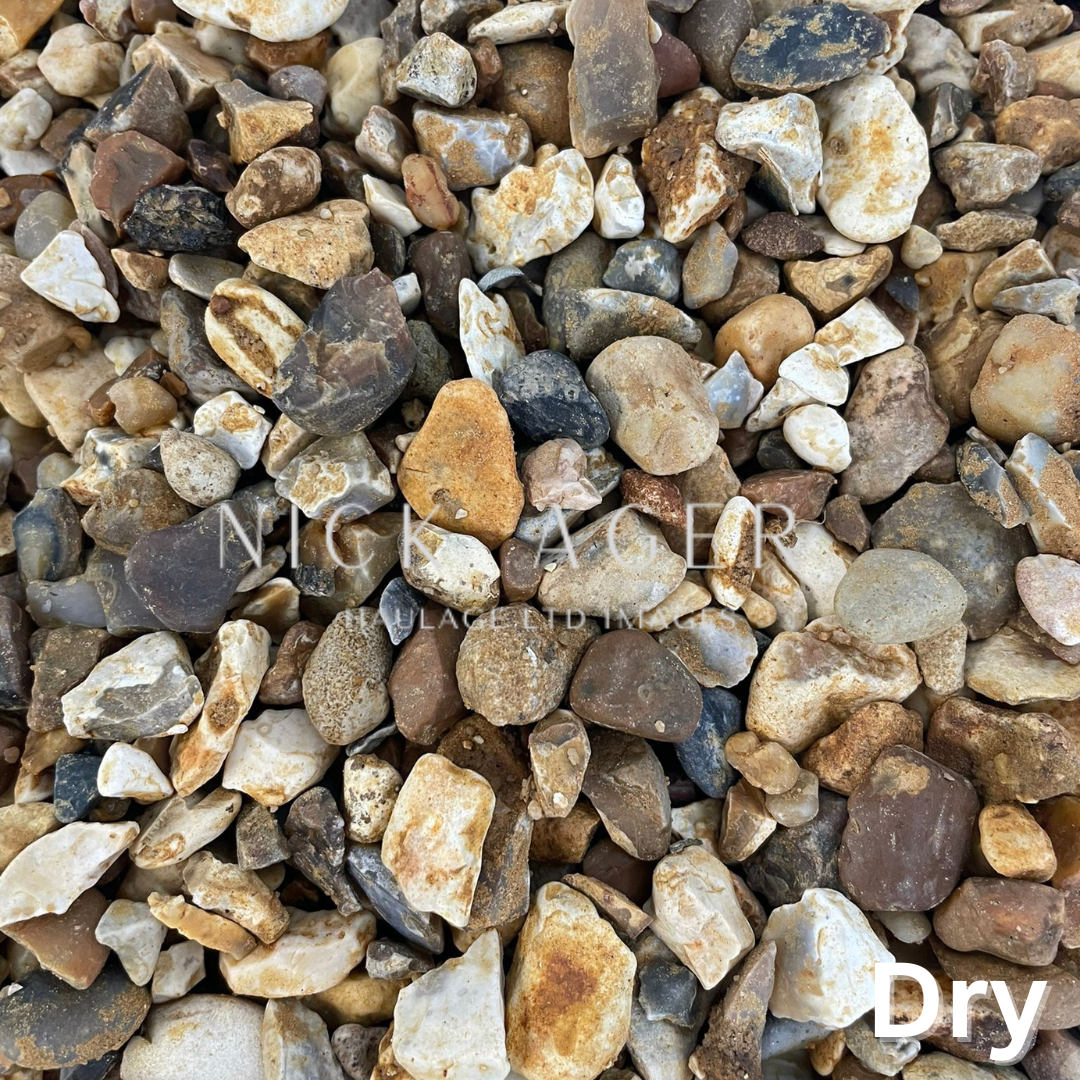 A close-up view of various sizes and colours of dry gravel stones, showcasing a mix of browns, whites, and greys.