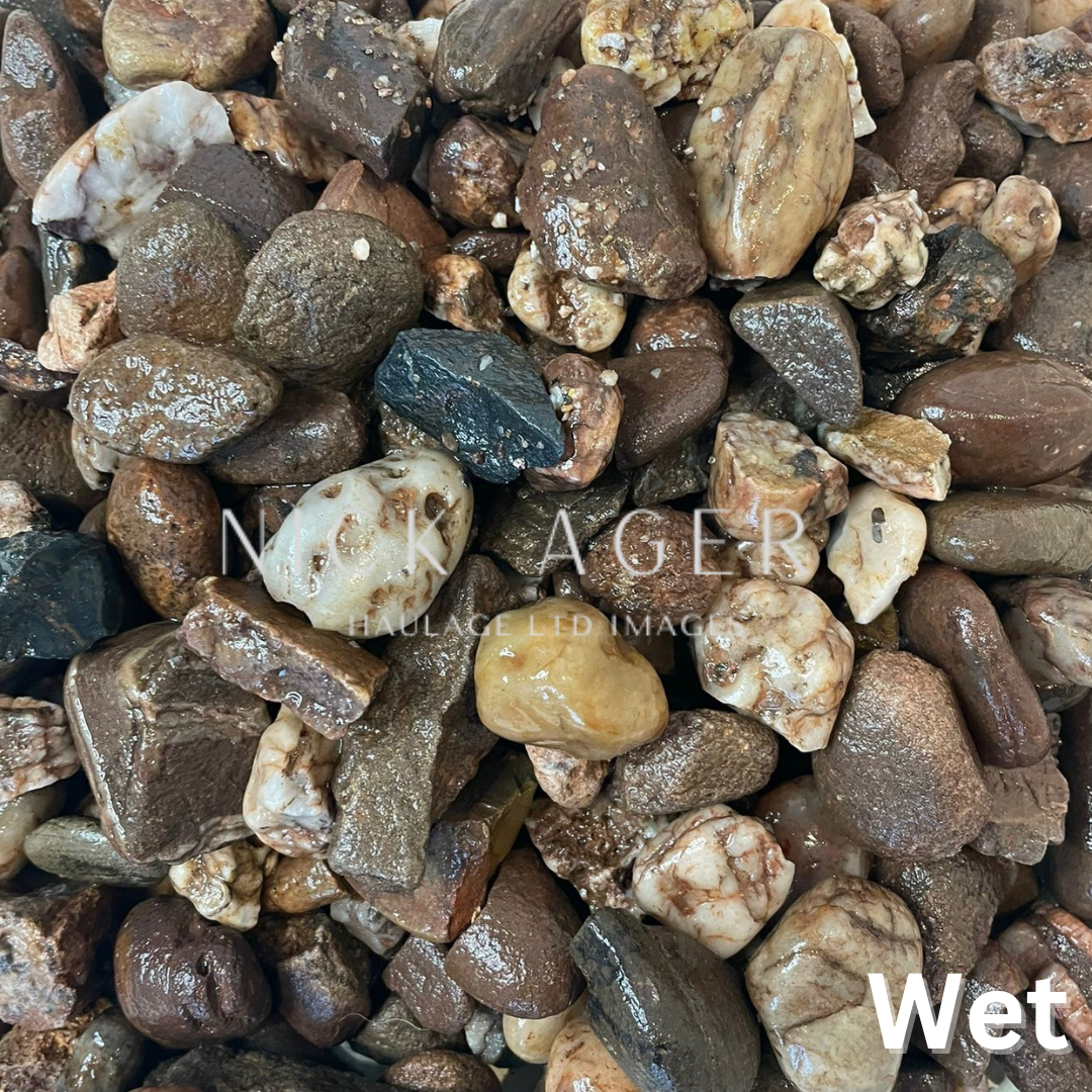 Close-up of assorted wet decorative stones, displaying various shapes and colours including brown, black, and cream.
