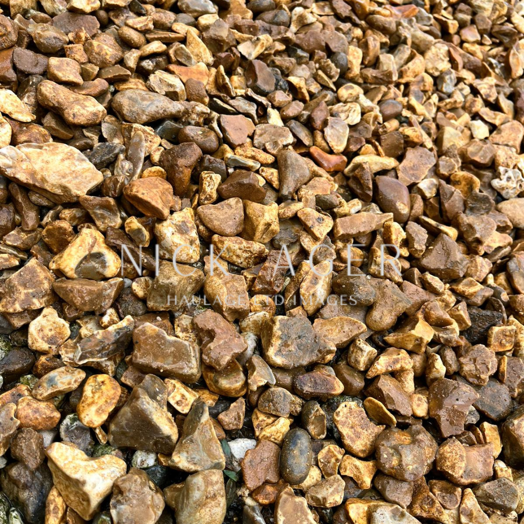 A close-up view of various small brown gravel stones with different shapes and sizes, displaying earthy tones and textures.