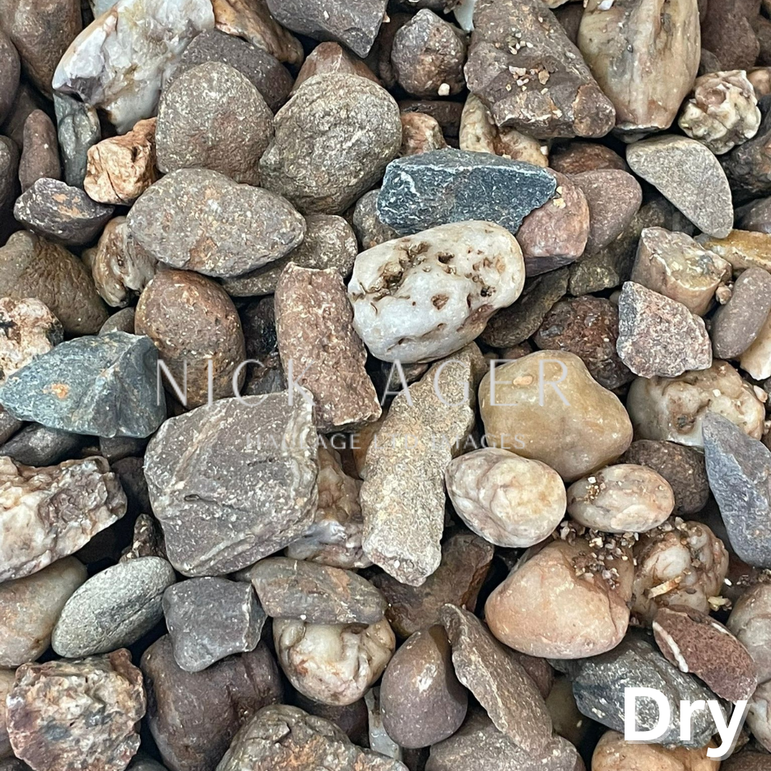A variety of dry decorative stones in different shapes and colours, including brown, grey, and white, scattered together.