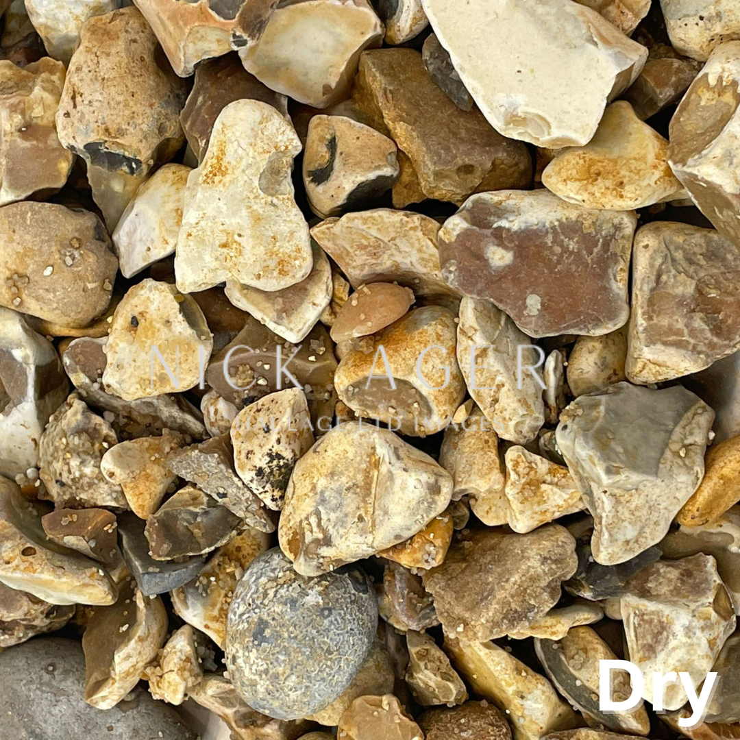 A close-up view of a variety of dry pebbles and stones in different shapes and colours including browns, greys, and whites.