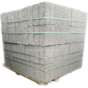 A large stack of grey foam blocks, secured with green straps, resting on a wooden pallet.