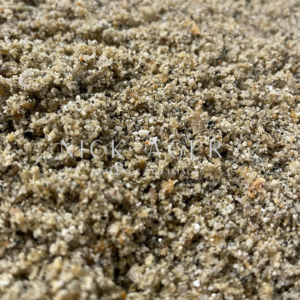 A detailed close-up view of a sandy texture with small grains in various shades of brown and beige.