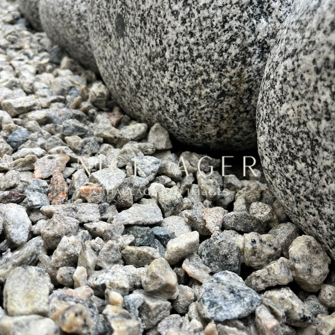 Close-up view of rounded granite stones resting on a bed of small grey pebbles.