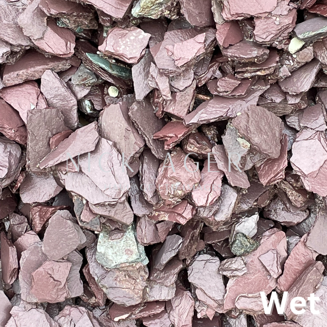 Close-up view of wet decorative slate chippings featuring a variety of shades from deep burgundy to grey.