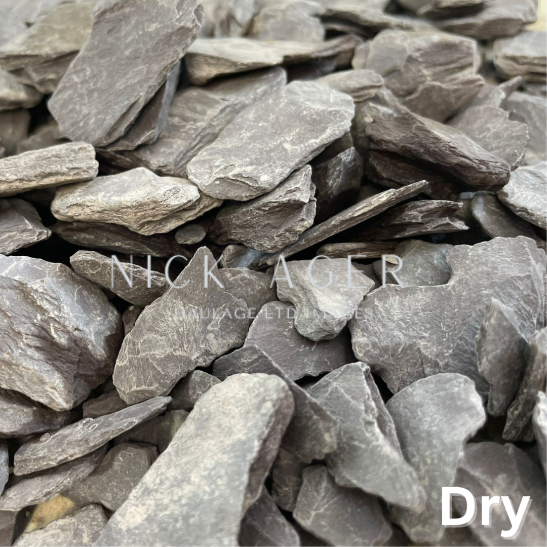 A close-up image of dry slate stones, showcasing their flat, irregular shapes and greyish hues.