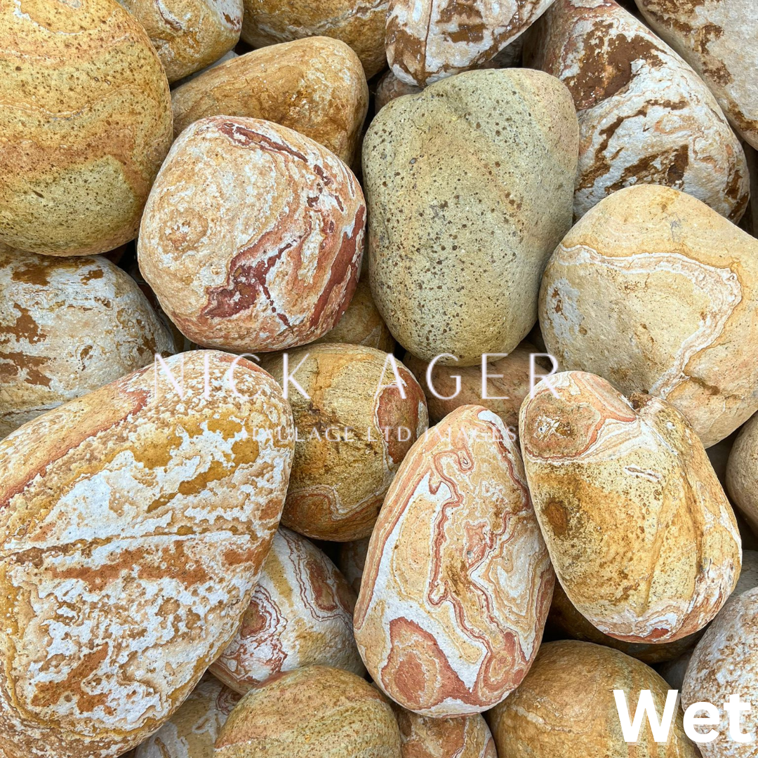 A close-up arrangement of smooth, multicoloured pebbles with unique patterns in shades of brown, yellow, and cream.