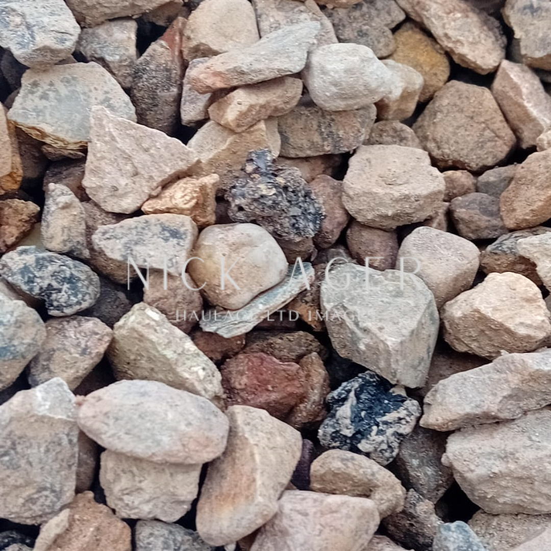 A close-up image showing a selection of small, multicoloured stones of various shapes and sizes, featuring earthy tones and textures.
