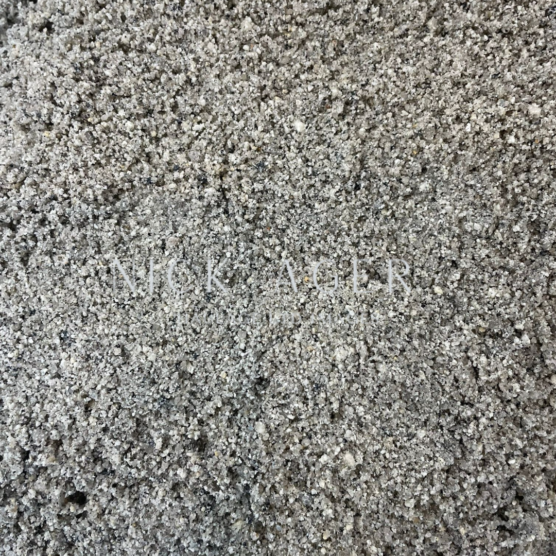 Close-up view of fine grey sand with a slightly grainy texture, featuring small particles and a uniform colour.