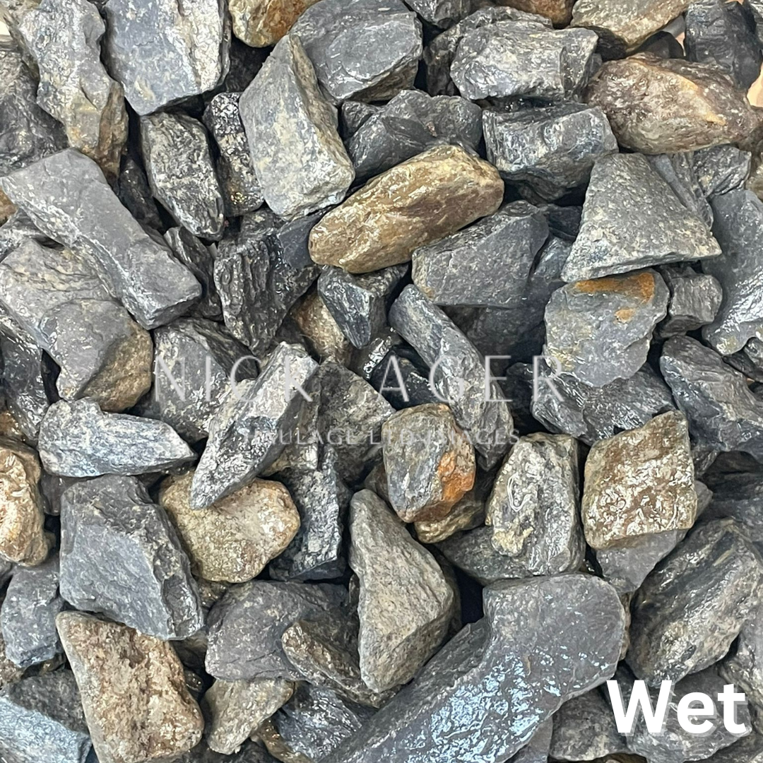 A close-up image of assorted wet grey and brown decorative stones in various shapes and sizes, showcasing a shiny surface due to moisture.
